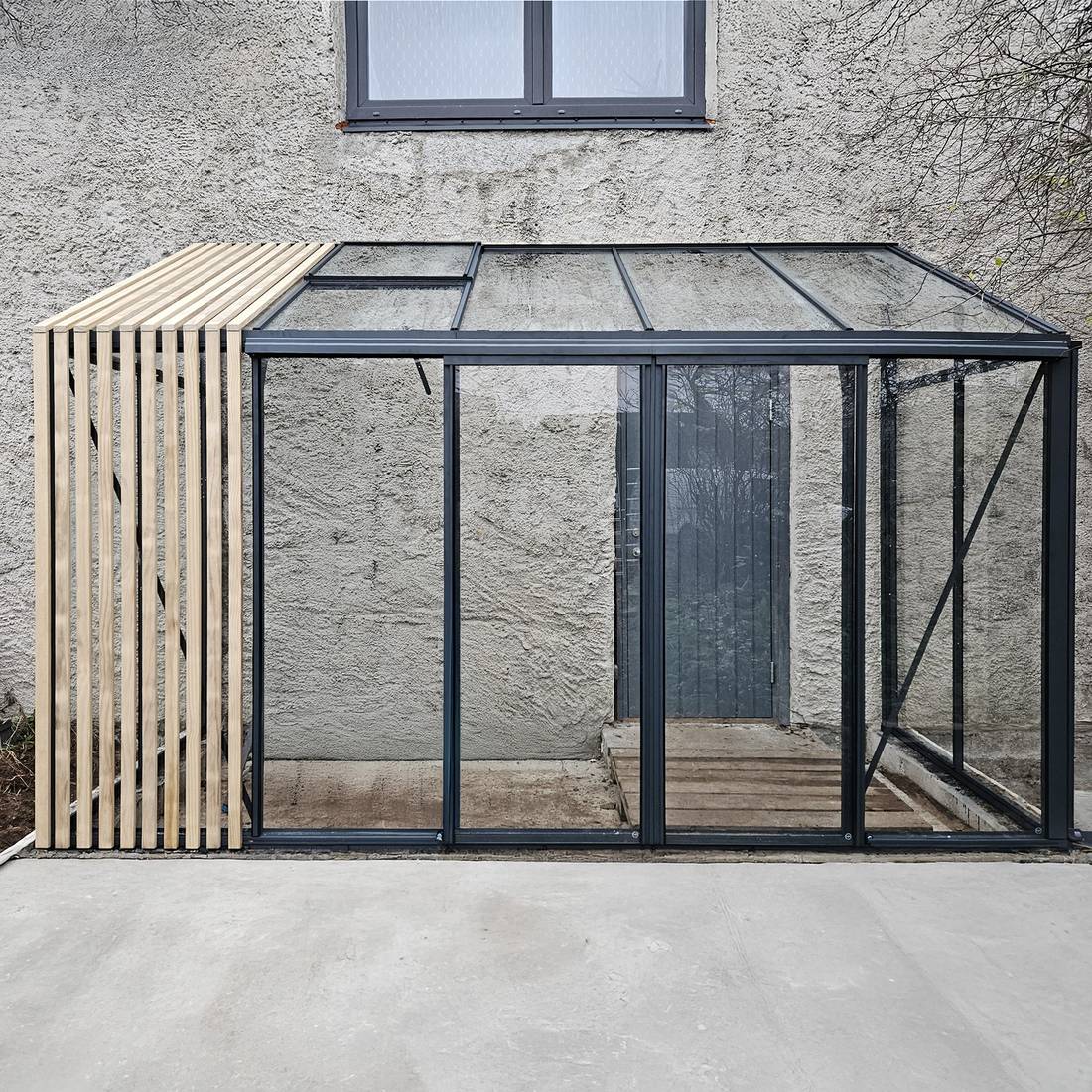 Veggmontert hagebygg med glassflater og kontrollert drenering