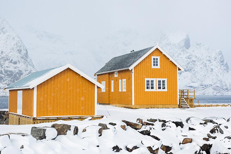 to-etasjes trehus på fjellet med vinduer og sprosser